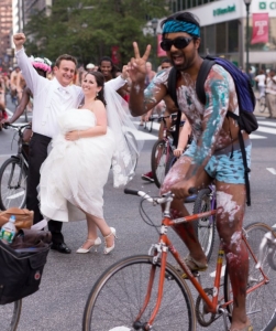 In this Saturday, Aug. 29, 2015 photo, Ross Cohen, left, and Blair Delson celebrate their wedding day at the edge of Dilworth Plaza in Philadelphia, as participants in the annual Philly Naked Bike Ride pass by. (Joseph Gidjunis/JPG Photography via AP)